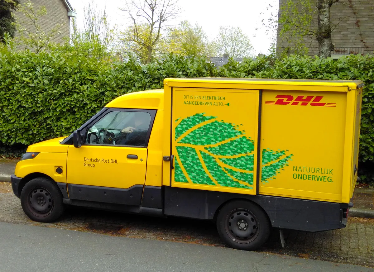 DHL elektrische bezorgbus levert pakketten af in woonwijk Nederland — transport goederenverzekering 2026