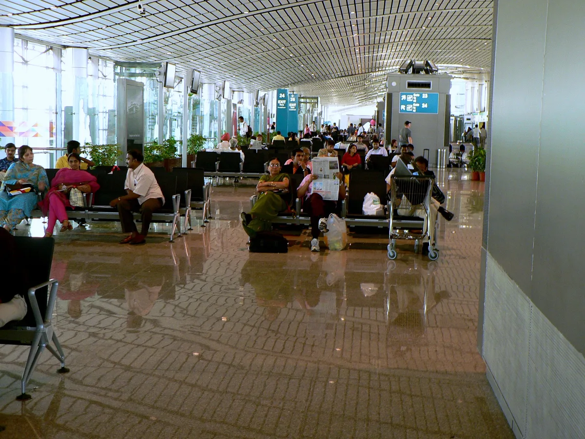 Reizigers wachten in de vertrekhal van luchthaven Rajiv Gandhi Hyderabad — last-minute reisverzekering afsluiten