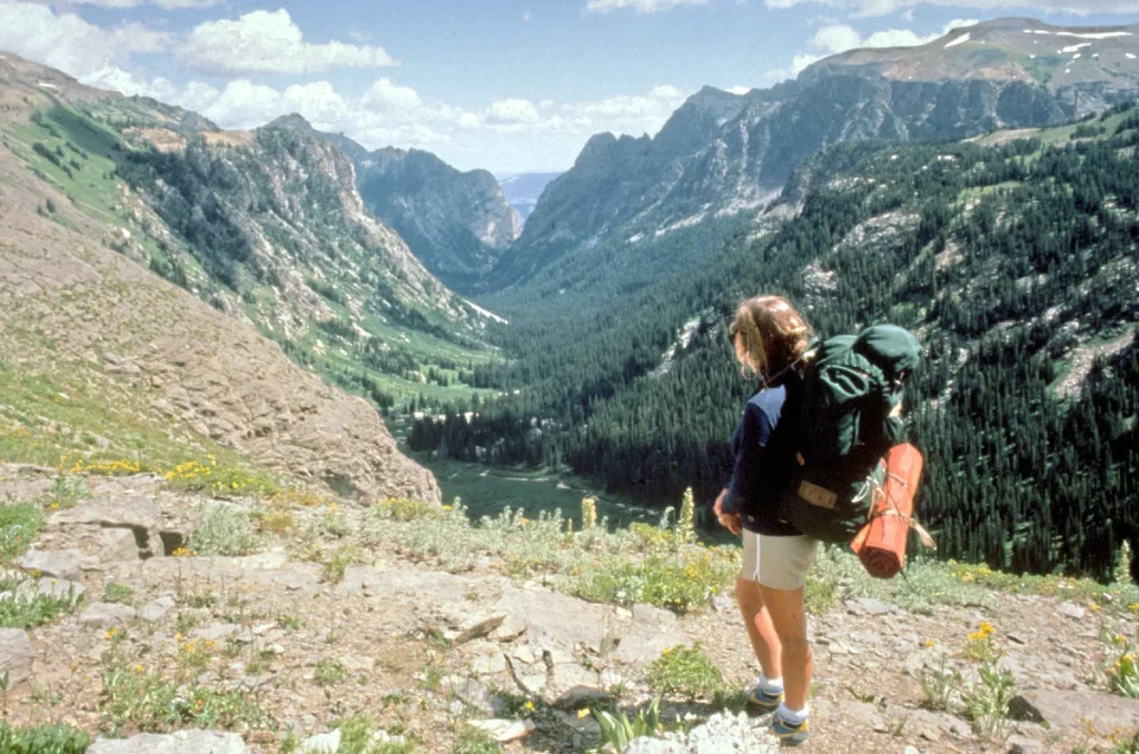 Backpacker met rugzak kijkt uit over berglandschap — reisverzekering voor lange backpackreis