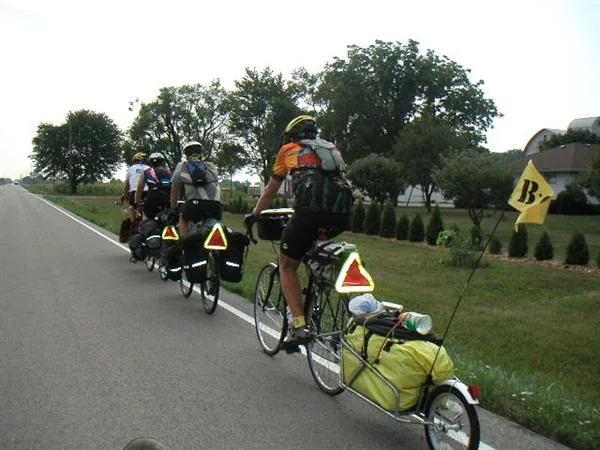 Fietsers op fietsvakantie met volle tassen en fietsaanhanger op een rechte asfaltweg
