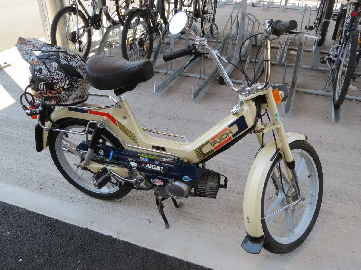 Puch Maxi S brommer klassieke oldtimer, creme met rode strepen, geparkeerd bij een fietsenstalling