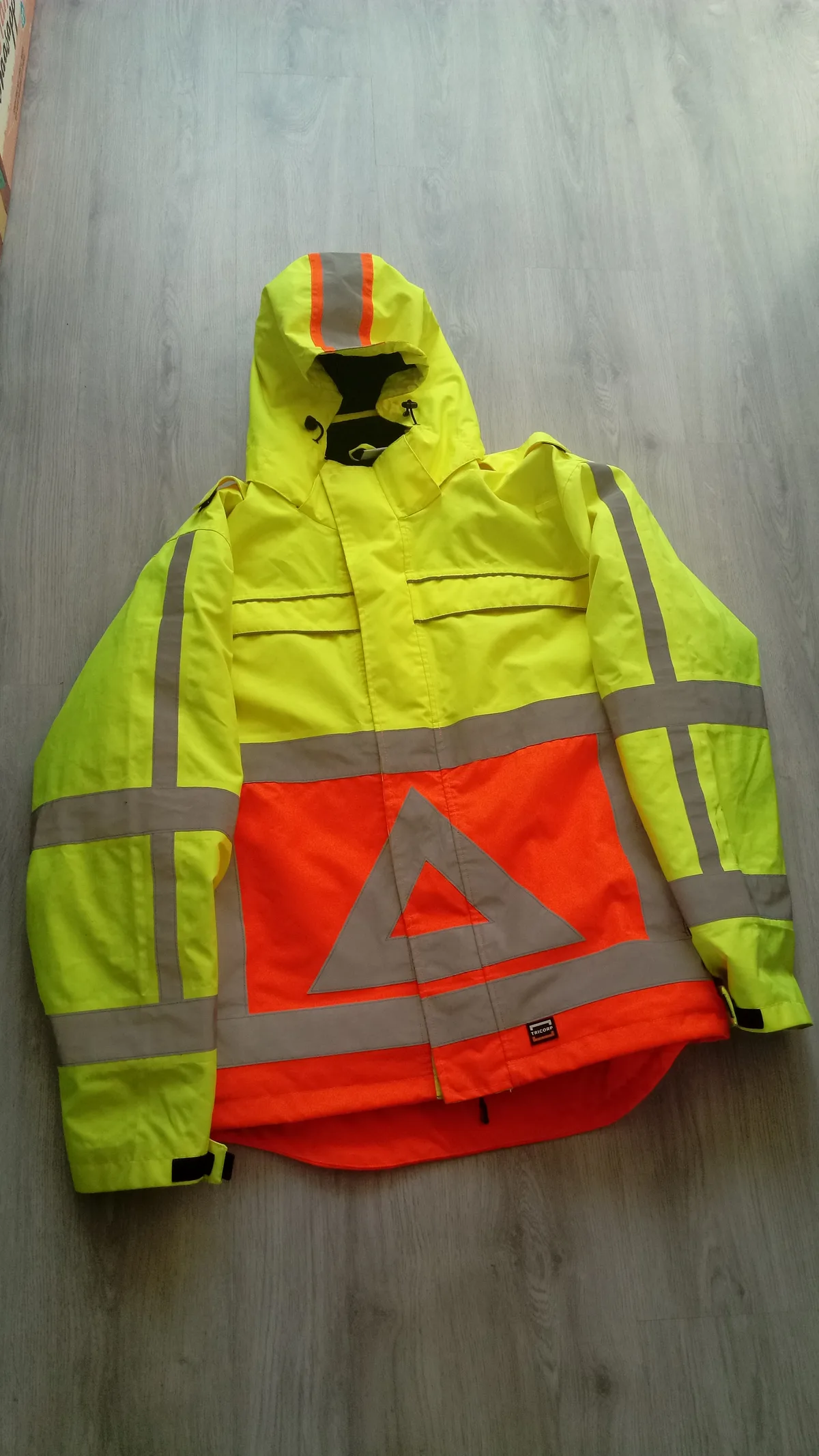 Fluorescerend geel-oranje jack van een Nederlandse verkeersregelaar met reflecterende driehoek en strepen