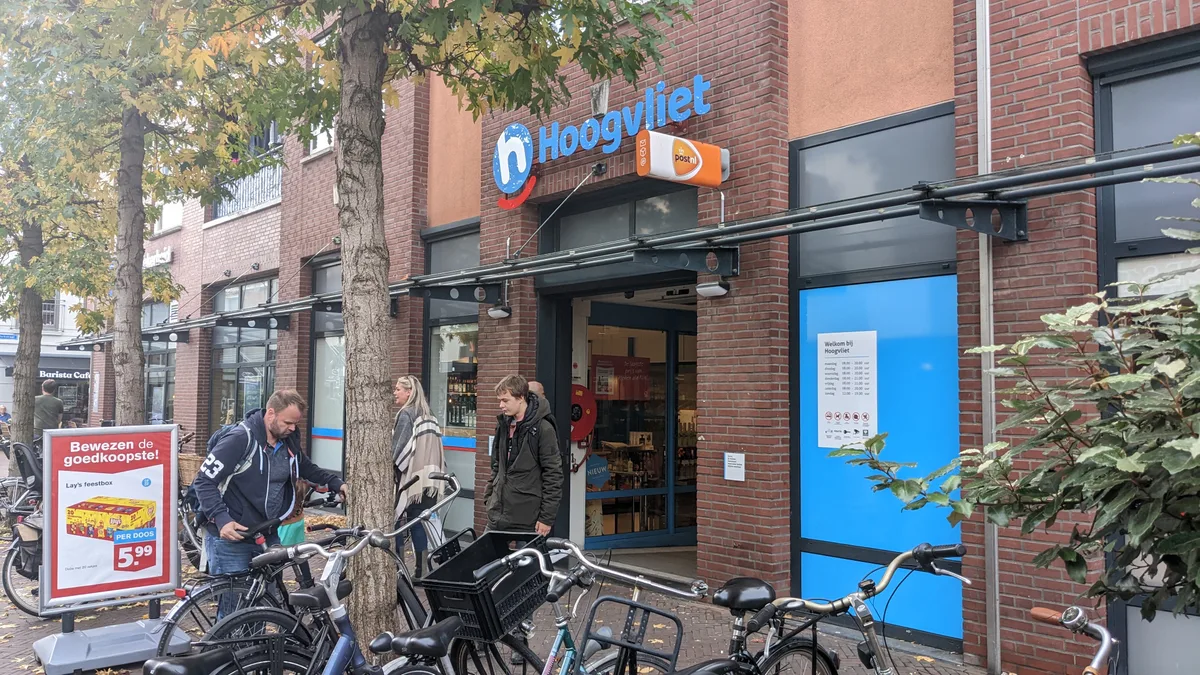 Exterieur van een Nederlandse winkel met klanten en fietsen voor de deur, illustratie winkelverzekering 2026