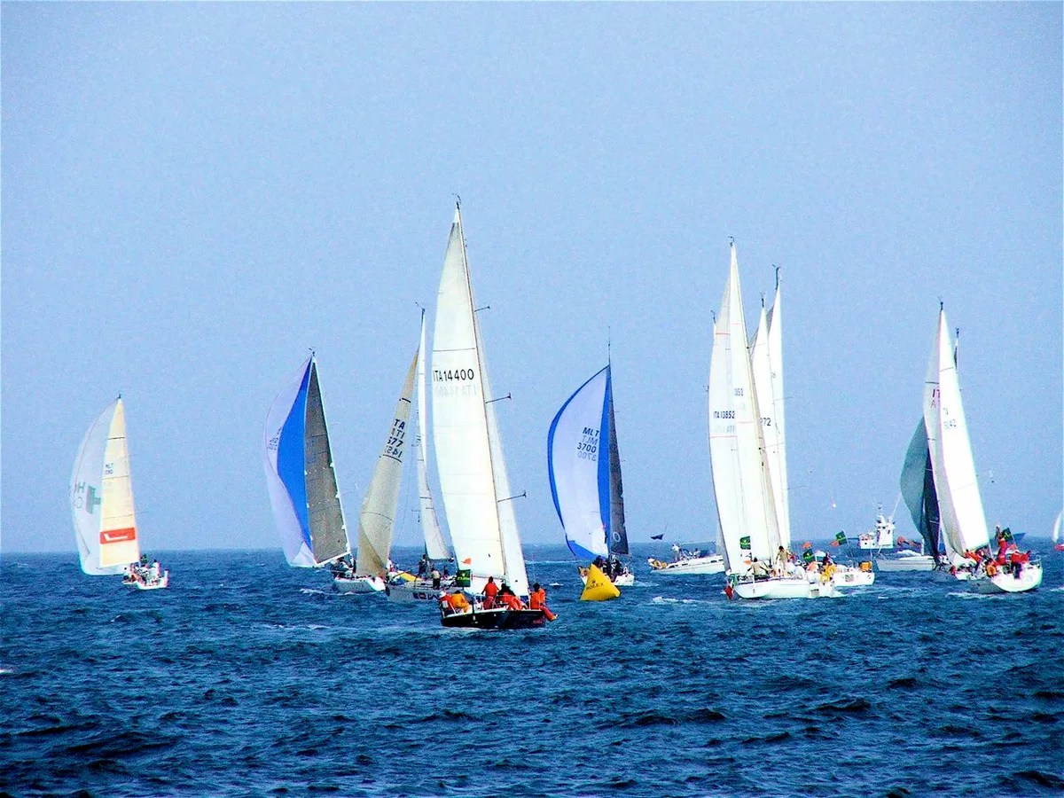 Meerdere zeiljachten tijdens een regatta-wedstrijd op open water met kleurrijke spinnakers