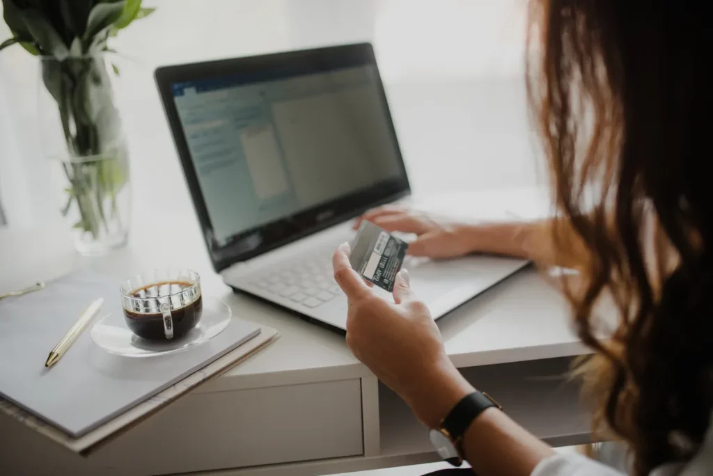 Vrouw bekijkt creditcard aan laptop bij online afsluiten van een verzekering zonder tussenpersoon