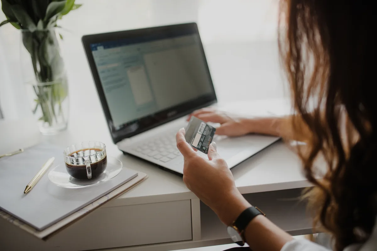 Vrouw bekijkt creditcard aan laptop bij online afsluiten van een verzekering zonder tussenpersoon