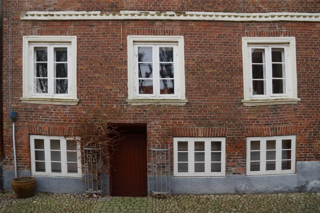 Verzakte woning met scheuren in metselwerk en verzakte vensterlijsten door bodemdaling in Denemarken