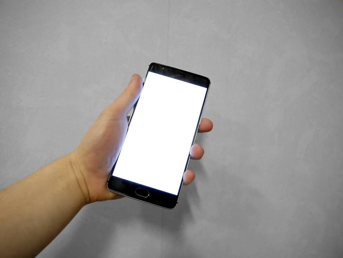 Hand houdt smartphone vast met wit scherm — symboliseert het opzeggen van een telefoonverzekering bij Vodafone