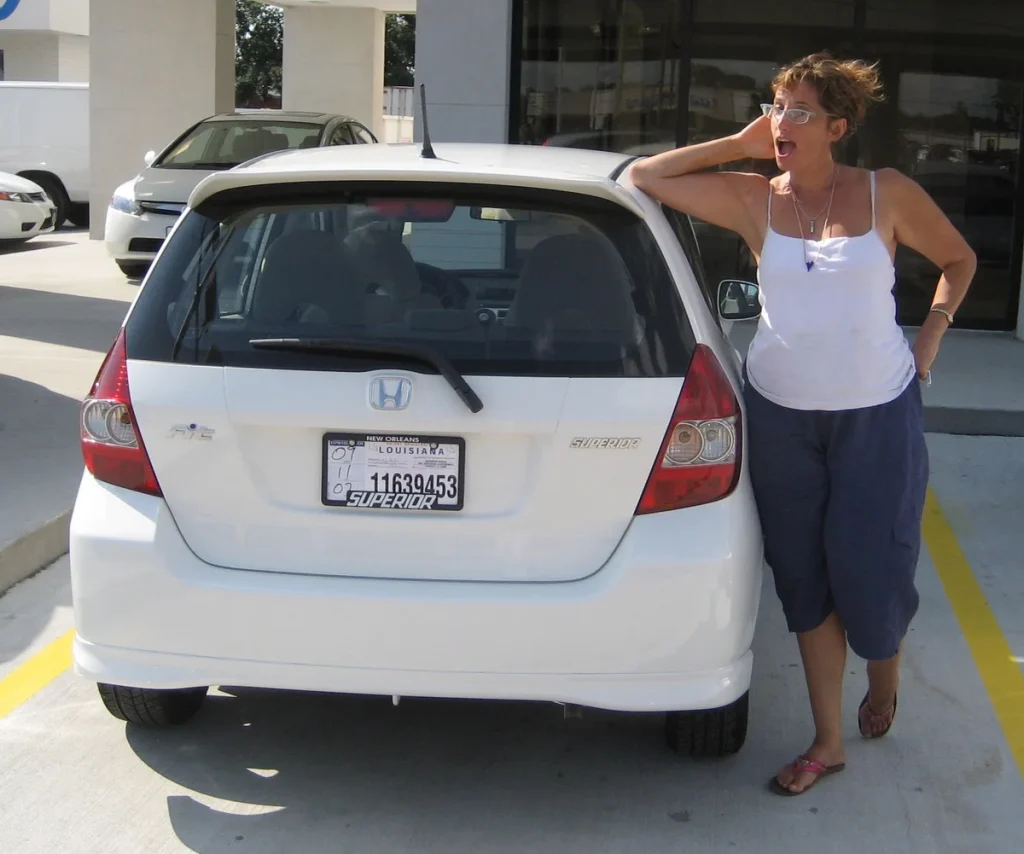 Vrouw poseert trots naast haar nieuwe Honda Fit bij een autodealer — voorlopige dekking auto direct geregeld