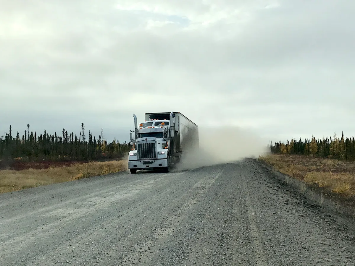 Vrachtwagen met oplegger rijdt over een onverharde weg, stof opwerpend — vrachtwagenverzekering dekking 2026