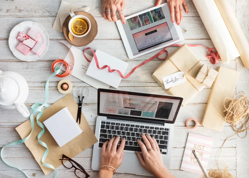 Persoon winkelt online via laptop en tablet met cadeaupakketten eromheen, webshop verzekering