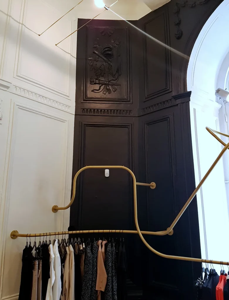 Interieur van een Nederlandse kledingboetiek met gouden kledingrekken en historische paneelwanden