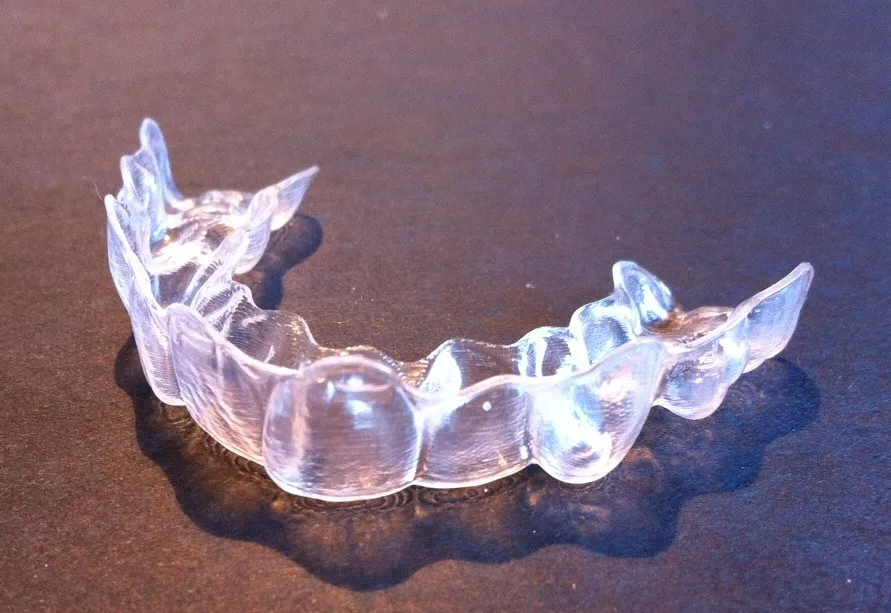 Transparante Invisalign aligner op donkere ondergrond — doorzichtige beugel voor orthodontische behandeling
