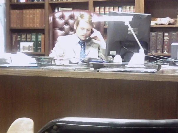 Advocaat aan bureau met juridische boeken op de achtergrond, zakelijke rechtsbijstand voor ondernemers