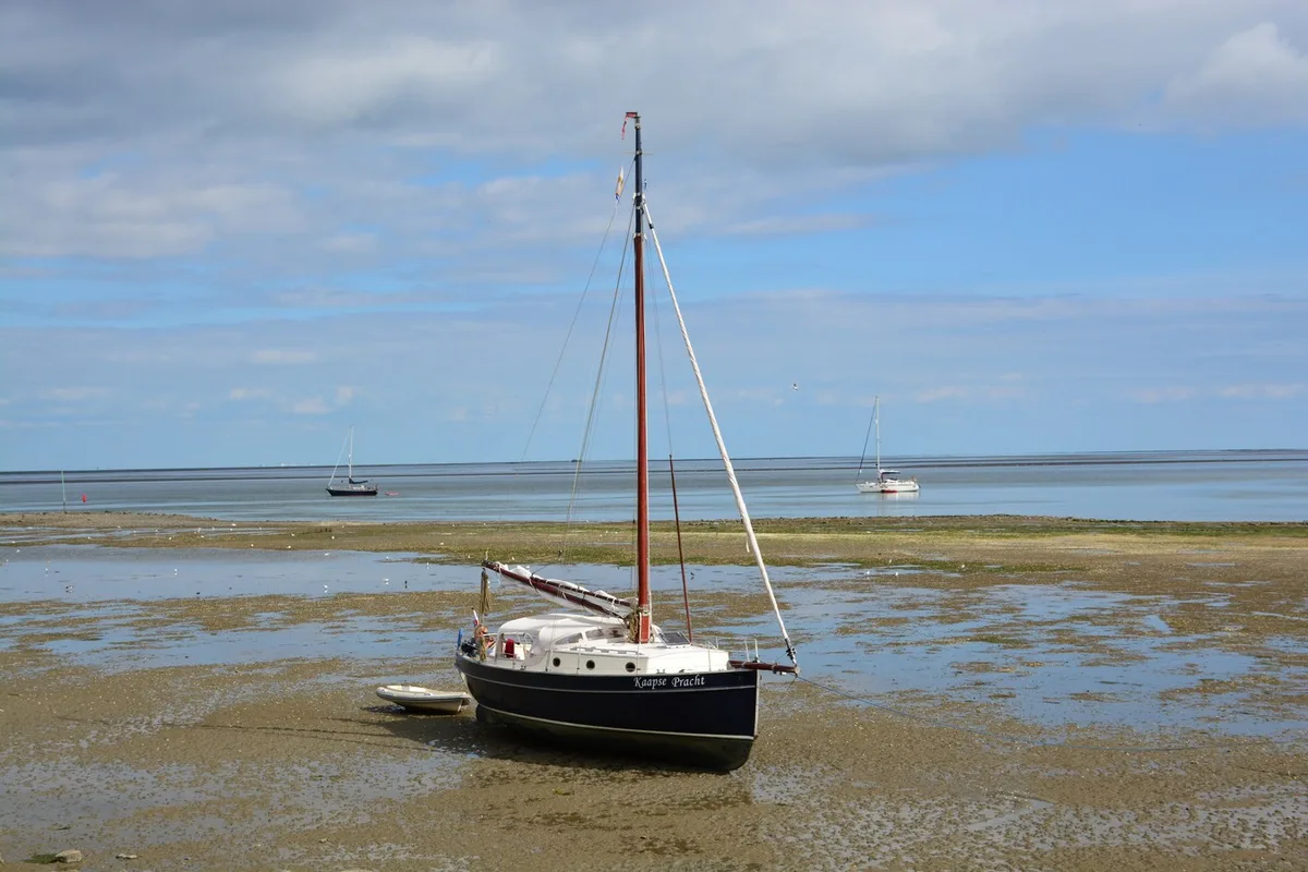 Zeiljacht drooggevallen op het wad bij Vlieland, Nederland - typisch beeld voor zeilen op de Waddenzee