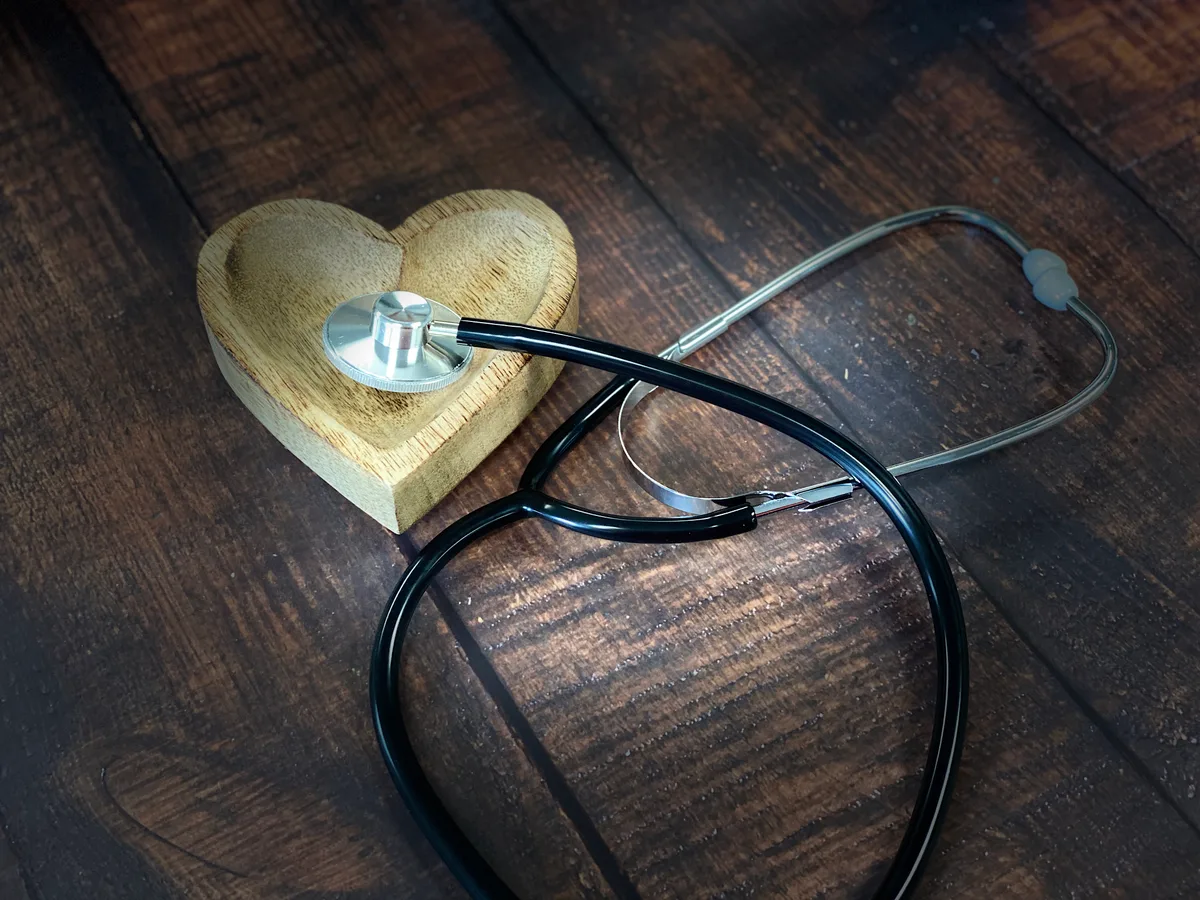 Stethoscoop met houten hart op donker hout — symbool voor zorgverzekering en gezondheid in 2026